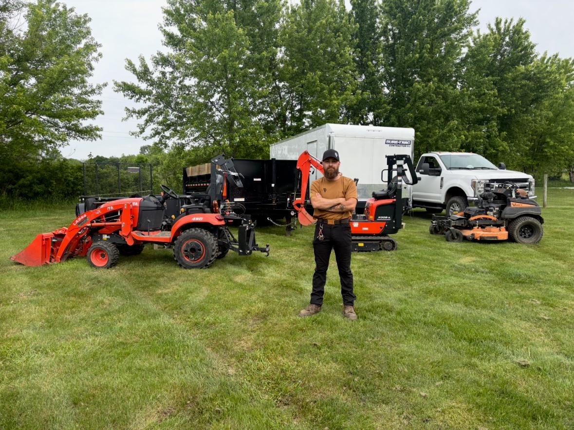 Steen's Lawn Care LLC owner standing with the company's tractor, mini excavator, dump trailer, and commercial mower